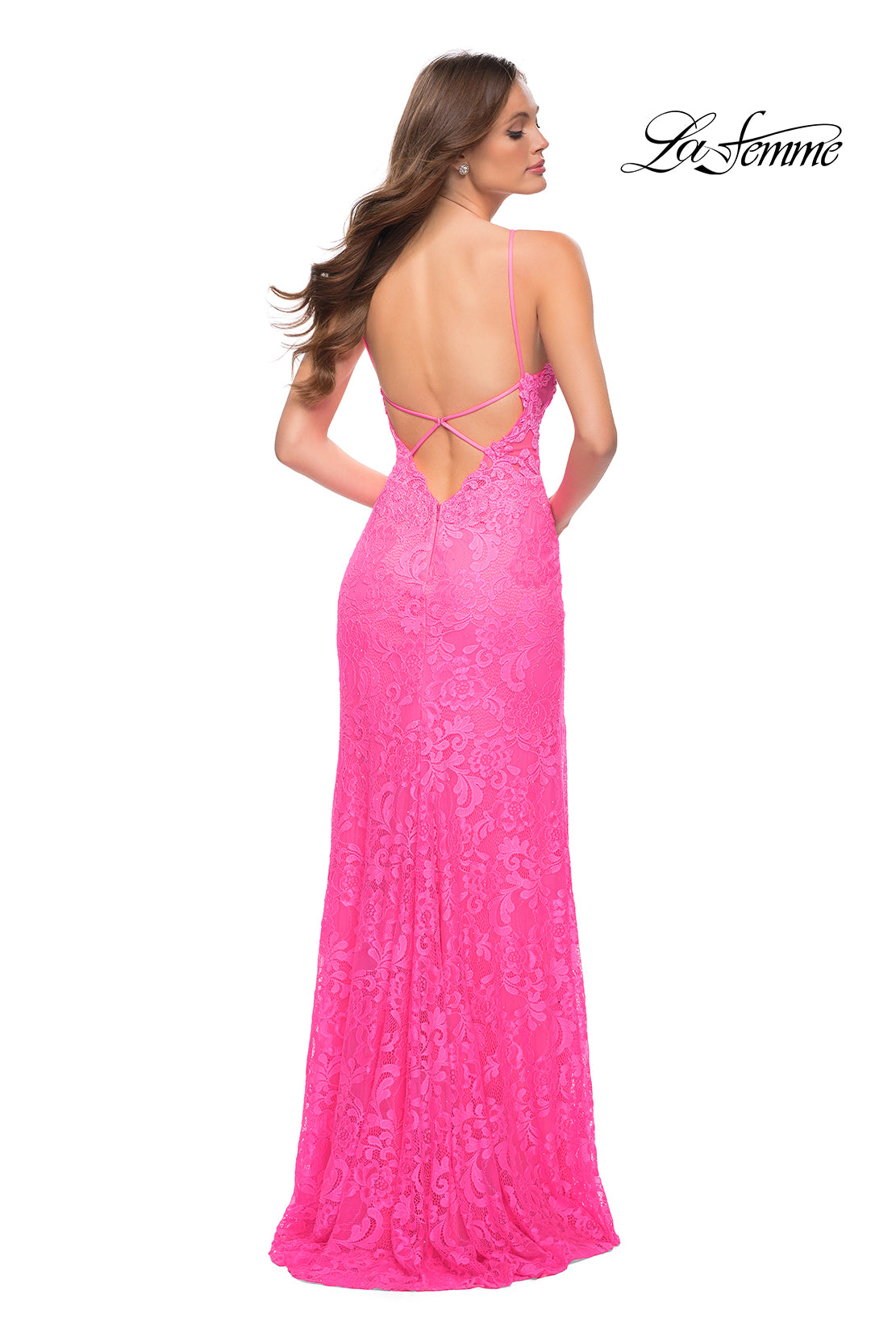 A woman faces away from the camera wearing the La Femme Open-Back Long Neon Lace Prom Dress in bright pink, featuring lace fabric, an open back, and thin straps. The La Femme logo appears in the top right corner.